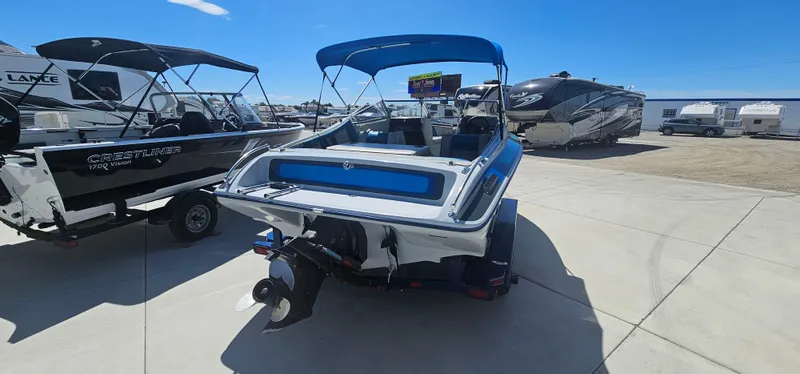 Slide: The Image of 1989 Galaxie 1900 Starion boat with blue canopy, parked in a marina lot. - 3