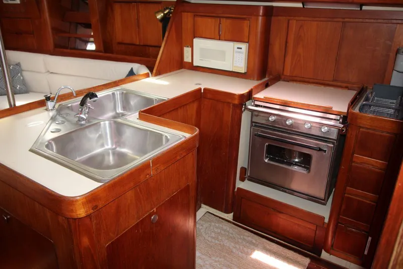 Slide: The Image of 1989 Pearson 39-2 yacht kitchen with dual sinks, stove, and microwave in wooden cabinetry. - 17
