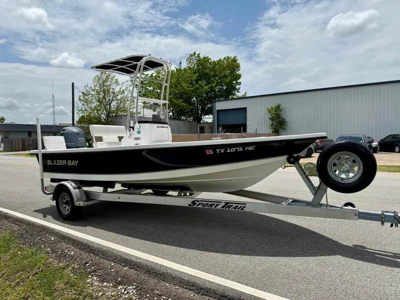 Slide: The Image of 2019 Blazer Bay 1900 boat on trailer, parked outdoors under cloudy sky. - 5