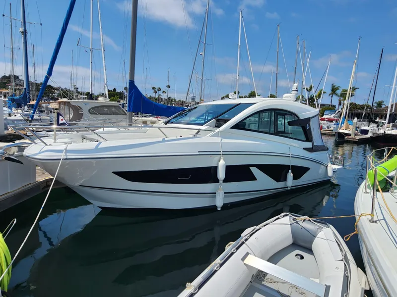 Slide: The Image of 2023 Beneteau GT32 yacht docked in a marina, surrounded by sailboats. - 2