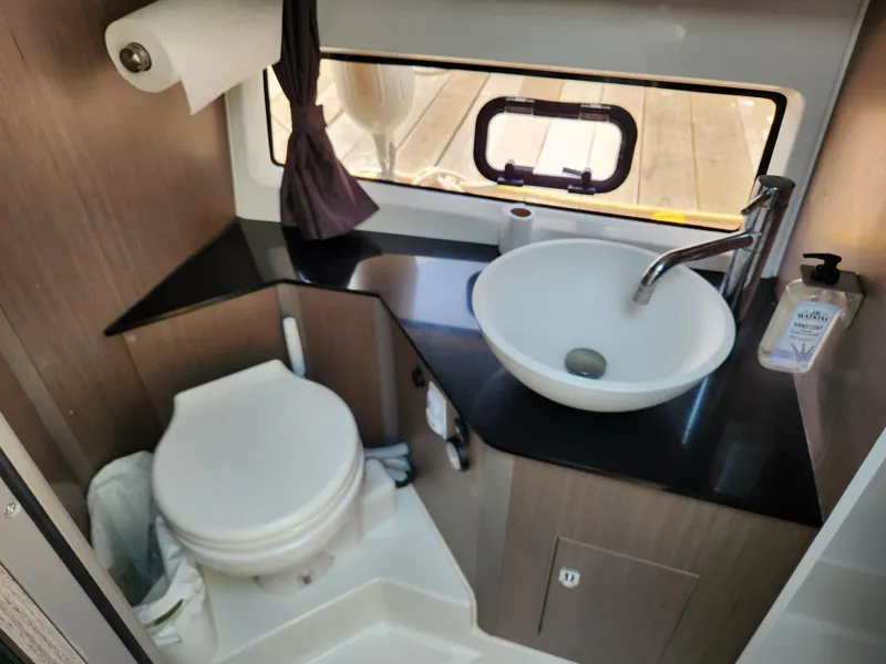 Slide: The Image of 2023 Beneteau GT32 bathroom with modern sink, toilet, and window view. - 24