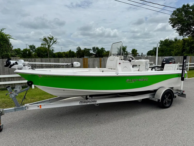 Slide: The Image of 2017 Blue Wave 2000 PureBay boat on trailer, green and white design, parked outdoors. - 1
