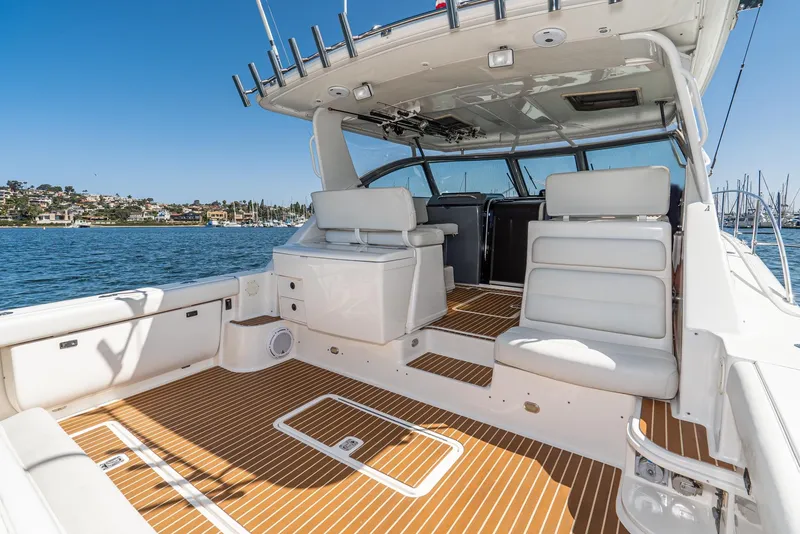 Slide: The Image of 2001 Tiara Yachts 3800 with spacious deck, white seating, and scenic waterfront view. - 11