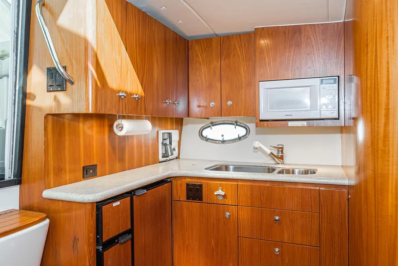 Slide: The Image of 2001 Tiara Yachts 3800 kitchen with wood cabinetry, sink, microwave, and compact fridge. - 38