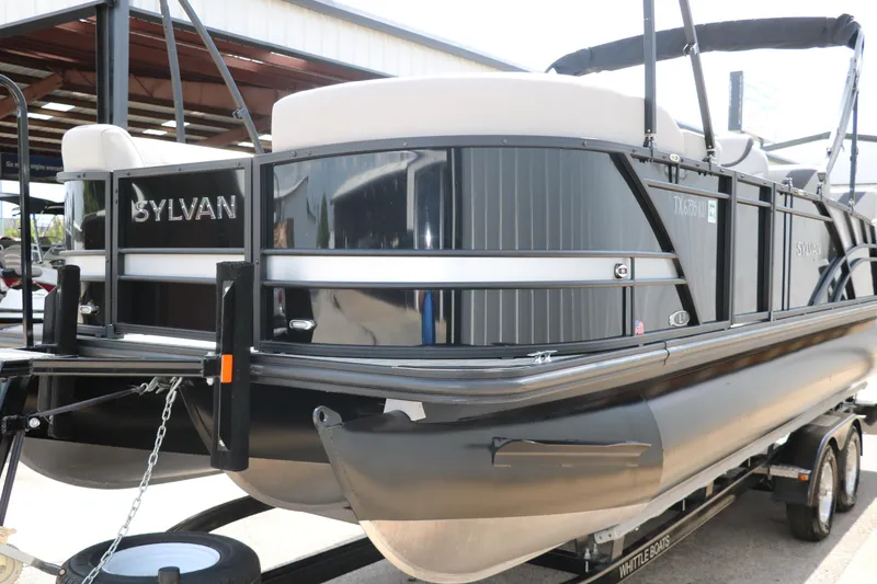 Slide: The Image of 2022 Sylvan L3 RLZ pontoon boat on trailer, black exterior, parked in a covered area. - 7