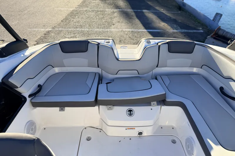 Slide: The Image of 2025 Yamaha Boats AR190 interior seating with gray cushions, dockside view. - 28