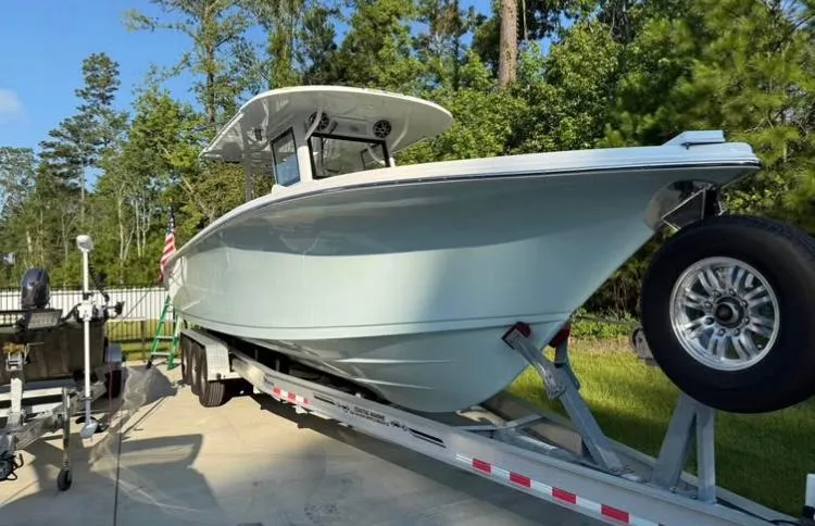 Slide: The Image of 2022 Sea Pro 320 DLX Offshore boat on trailer, surrounded by trees. - 2