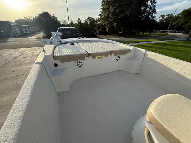 Slide: The Image of 2016 Carolina Skiff 238DLV boat interior with seating and storage, parked outdoors. - 12