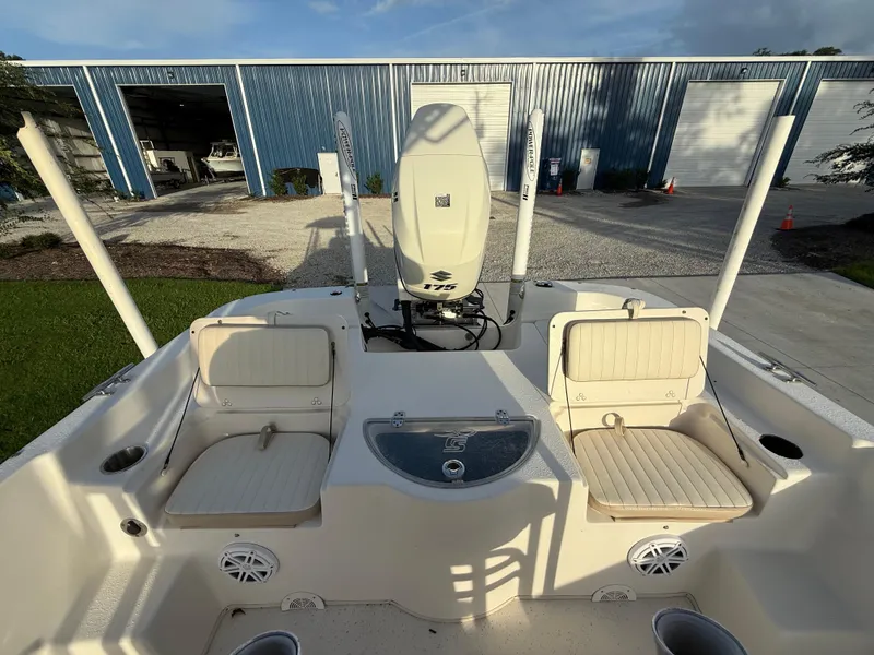 Slide: The Image of 2016 Carolina Skiff 238DLV boat interior with seating and motor, parked near blue warehouse. - 19