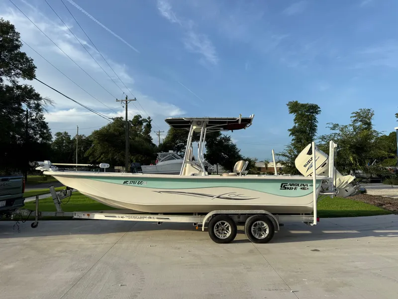 Slide: The Image of 2016 Carolina Skiff 238DLV boat on trailer, parked outdoors under clear sky. - 2
