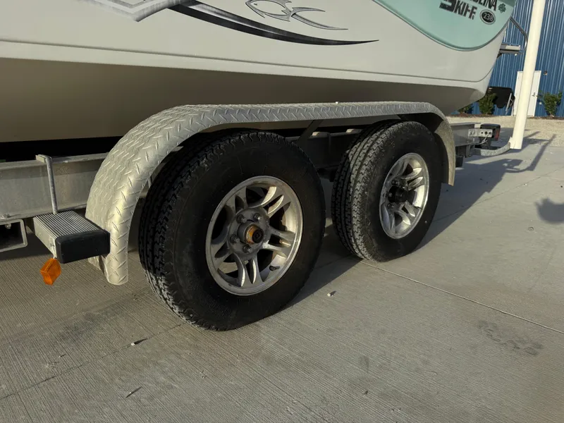 Slide: The Image of Trailer with dual wheels for 2016 Carolina Skiff 238DLV boat on concrete surface. - 23