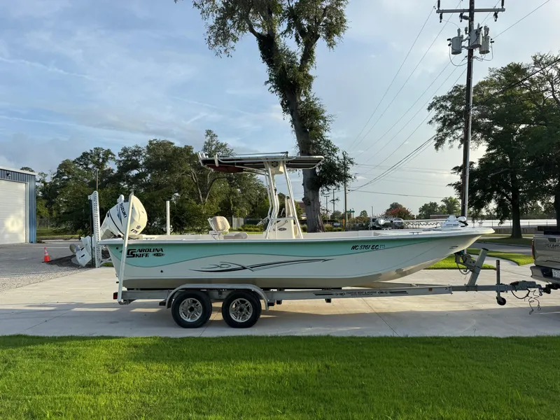 Slide: The Image of 2016 Carolina Skiff 238DLV boat on trailer, parked outdoors near trees and power lines. - 5