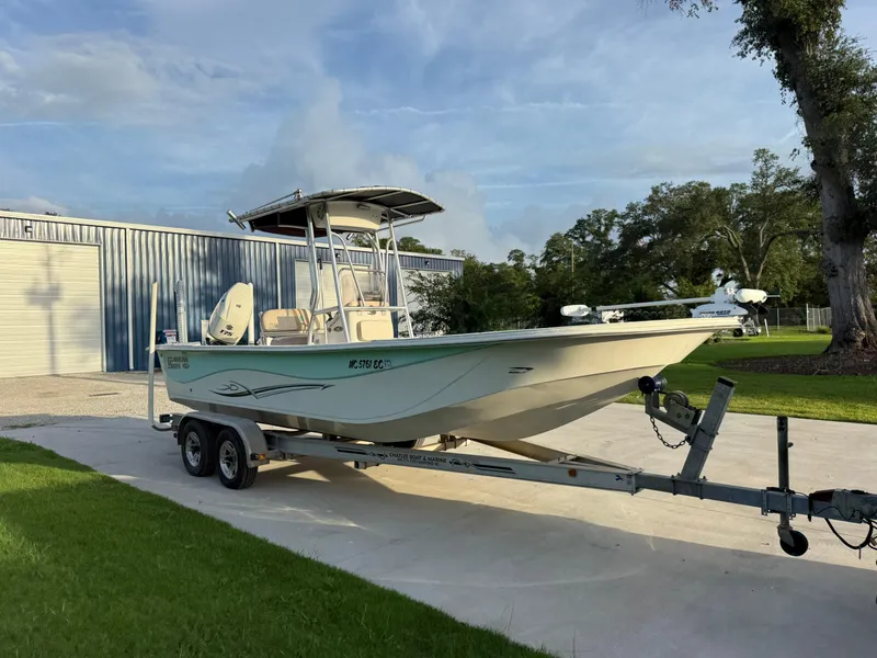 Slide: The Image of 2016 Carolina Skiff 238DLV boat on trailer, parked near a metal building. - 6