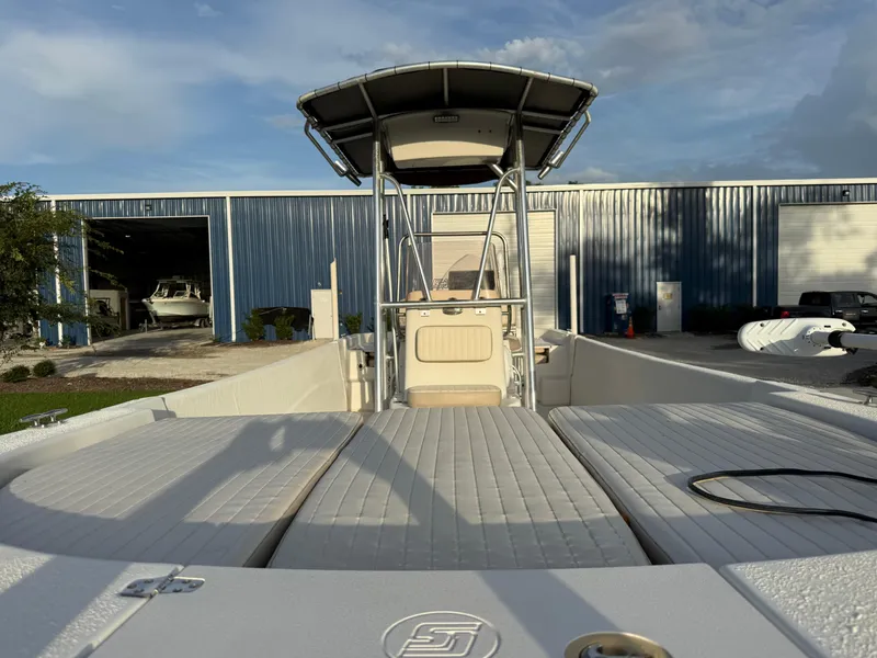 Slide: The Image of 2016 Carolina Skiff 238DLV boat docked near blue warehouse under clear sky. - 9