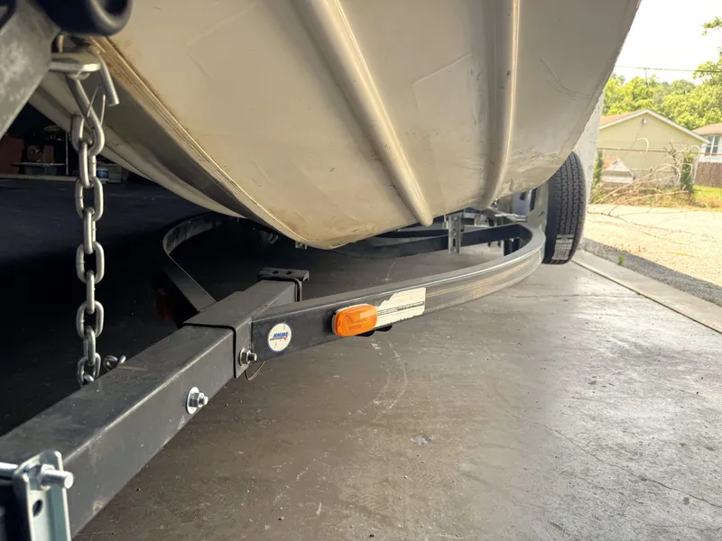 Slide: The Image of 2004 Lowe 170W boat on trailer, showing underside and chain, parked in driveway. - 8