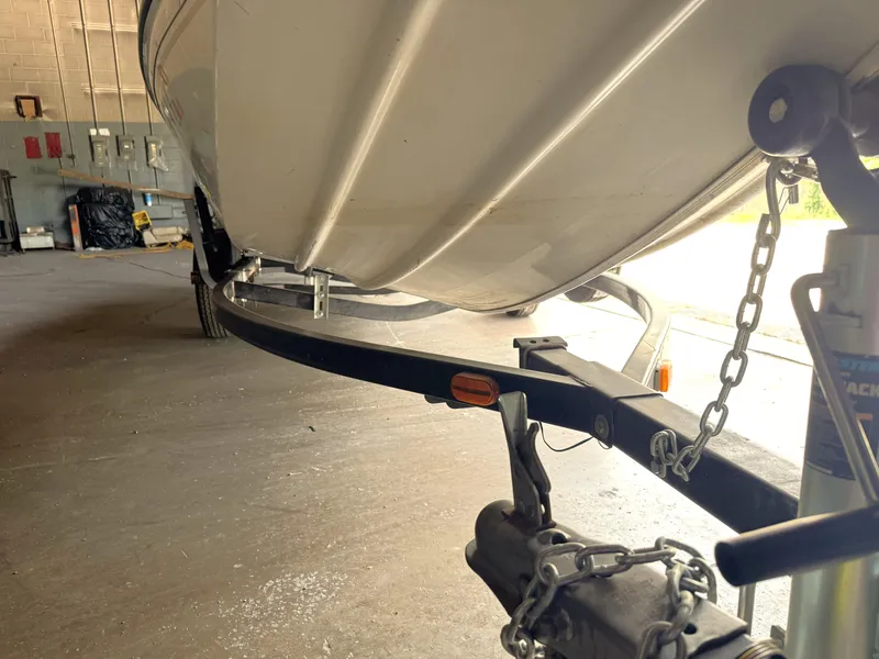Slide: The Image of 2004 Lowe 170W boat on trailer in garage, showing underside and hitch details. - 9