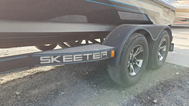 Slide: The Image of 2017 Skeeter ZX 250 boat trailer with dual wheels on gravel surface. - 7