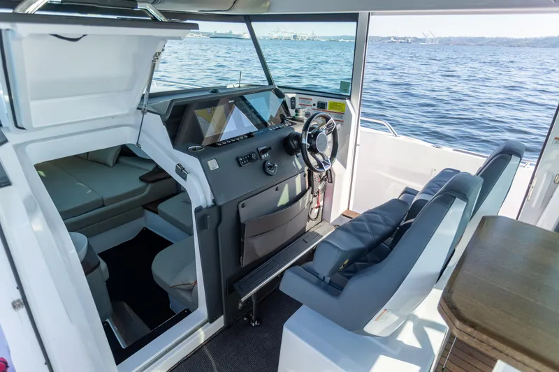 Slide: The Image of 2021 Axopar 37XC Aft Cabin interior with helm, seating, and ocean view. - 27
