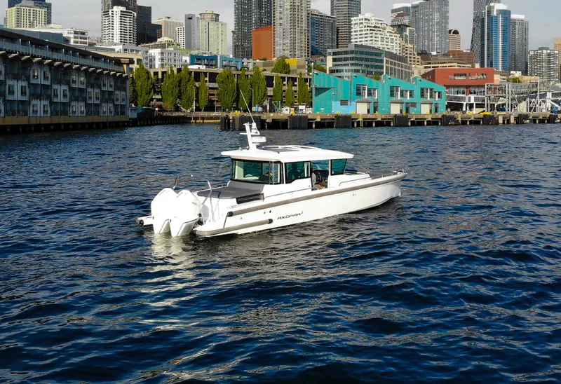 Slide: The Image of 2021 Axopar 37XC Aft Cabin boat cruising near urban waterfront skyline. - 3