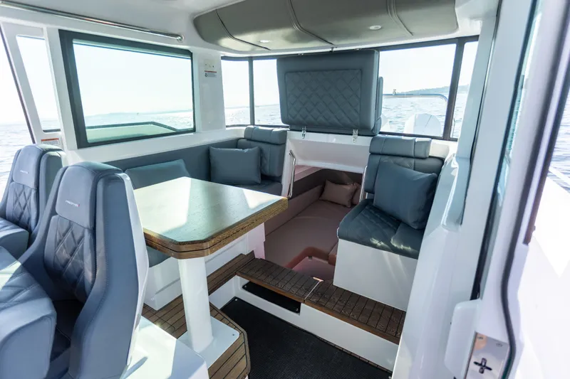 Slide: The Image of Interior of 2021 Axopar 37XC Aft Cabin with seating and table, overlooking the sea. - 35
