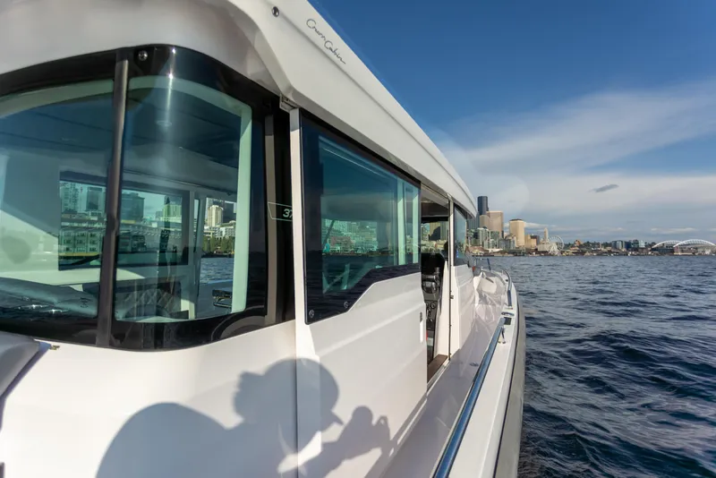 Slide: The Image of Axopar 37XC Aft Cabin 2021 cruising near a city skyline on a sunny day. - 7