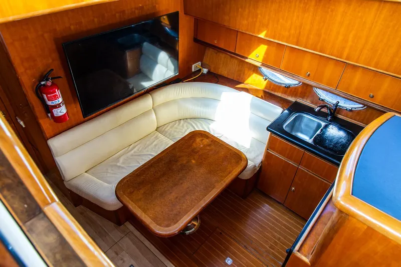 Slide: The Image of Luxurious 2002 Dyna 50 yacht interior with seating, table, TV, and kitchenette. - 25