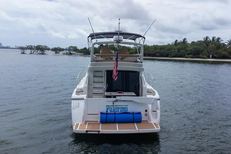 Slide: The Image of 2002 Dyna 50 yacht on water, American flag, lush shoreline in background. - 3