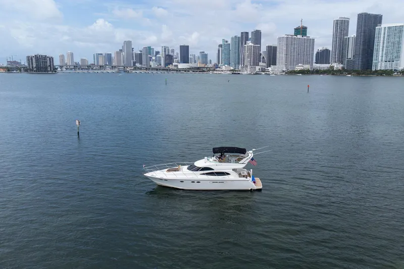 Slide: The Image of A 2002 Dyna 50 yacht cruising near a city skyline on a calm, sunny day. - 5
