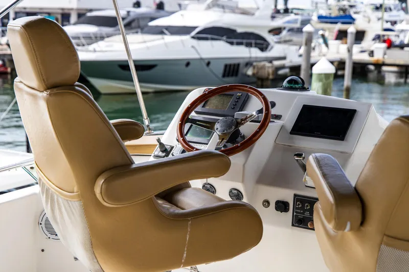 Slide: The Image of Captain's chair and helm of a 2002 Dyna 50 yacht, docked at a marina. - 9