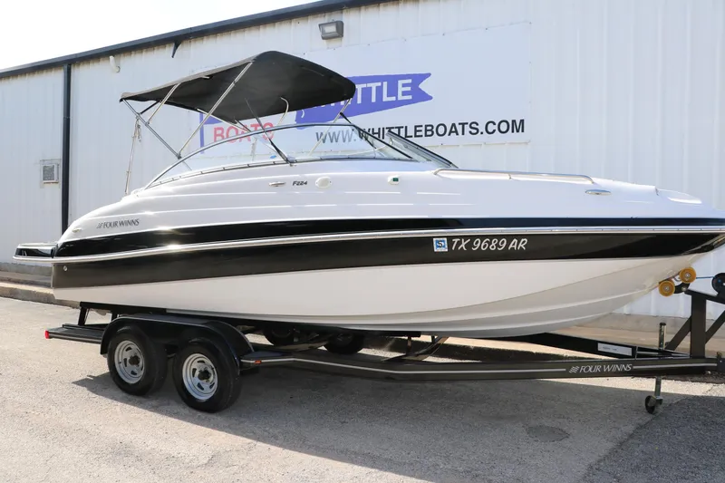 Slide: The Image of 2008 Four Winns 224 Funship boat on trailer, black and white design, parked outside. - 6