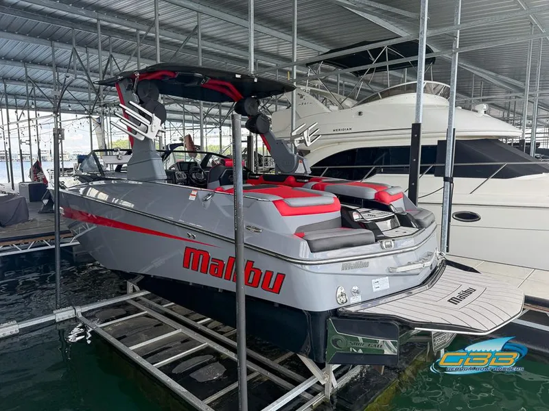 Slide: The Image of 2019 Malibu M235 boat in marina, featuring sleek design and red accents. - 12