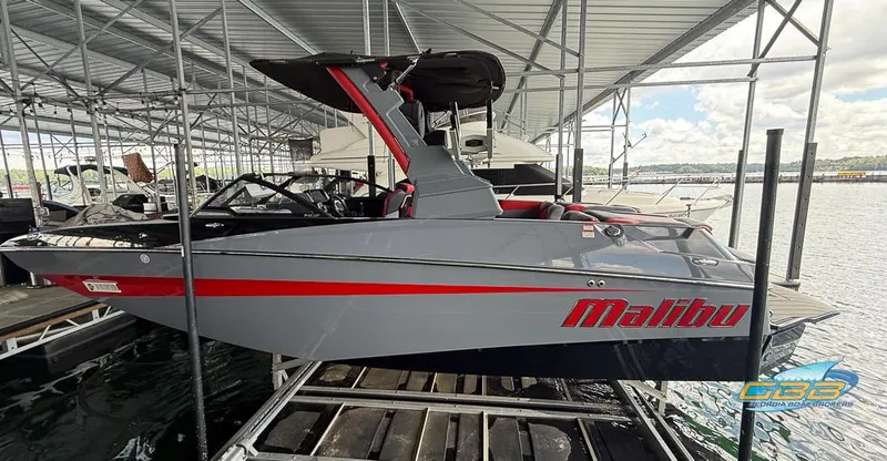 Slide: The Image of 2019 Malibu M235 boat docked in a marina, featuring sleek gray and red design. - 13