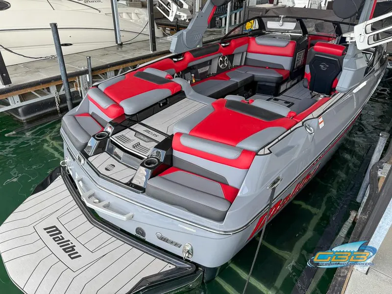Slide: The Image of 2019 Malibu M235 boat with red and gray seating, docked in water. - 14
