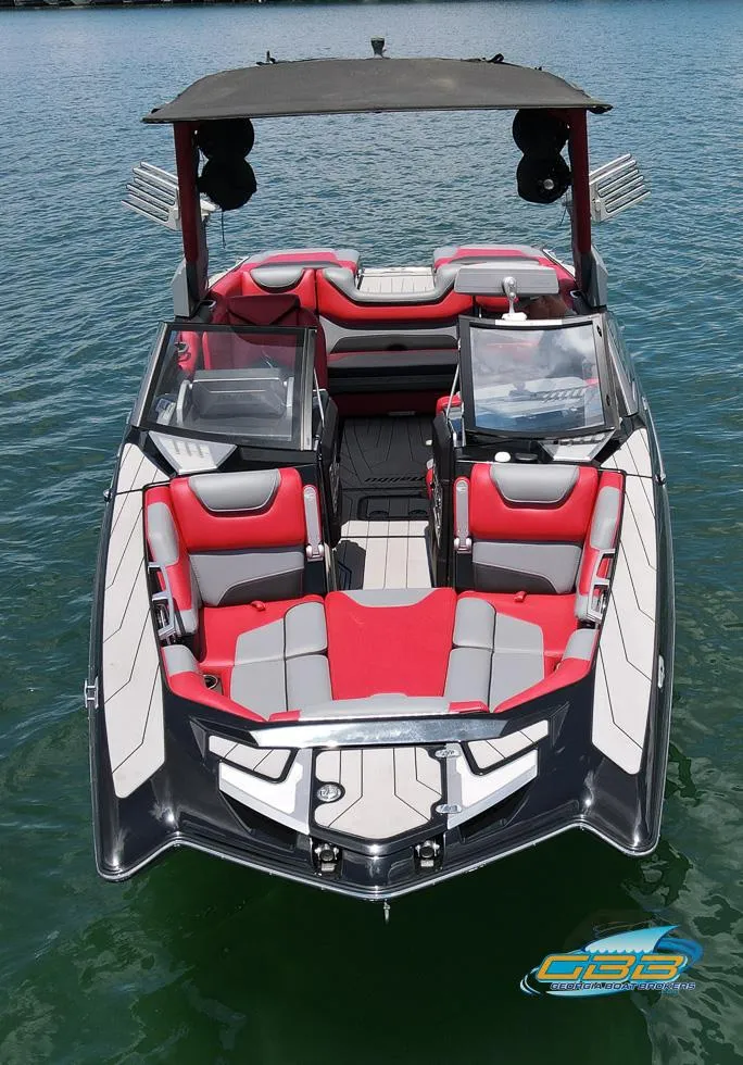 Slide: The Image of 2019 Malibu M235 boat with red and gray seating, floating on water. - 2