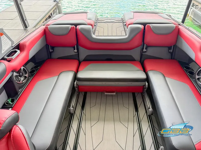 Slide: The Image of Red and gray interior seating of a 2019 Malibu M235 boat, docked by the water. - 22