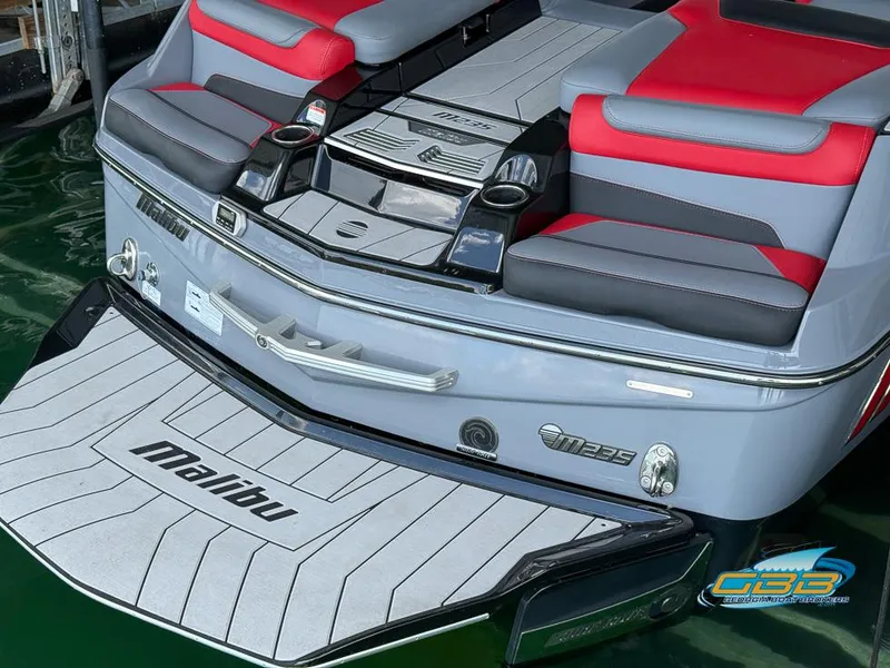 Slide: The Image of 2019 Malibu M235 boat with red and gray seating, docked on water. - 29