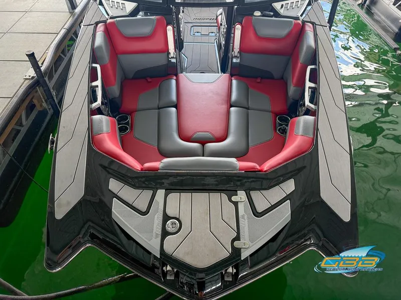 Slide: The Image of 2019 Malibu M235 boat interior with red and gray seating, docked on green water. - 30