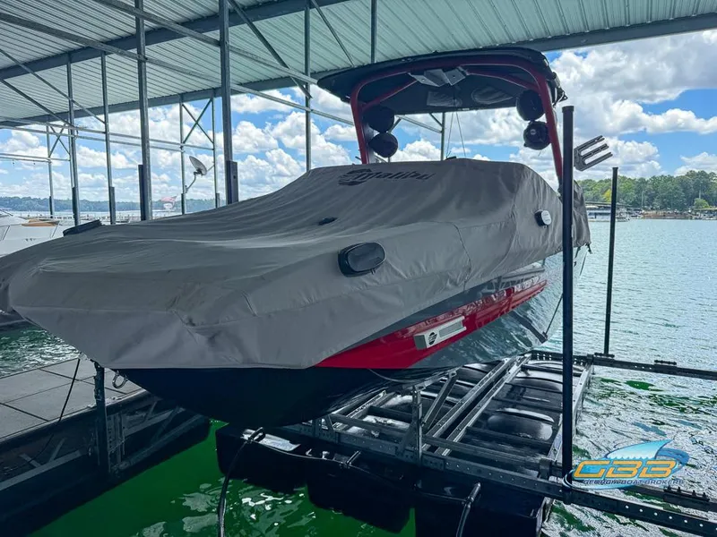 Slide: The Image of 2019 Malibu M235 boat covered and docked on a lift at a marina. - 31