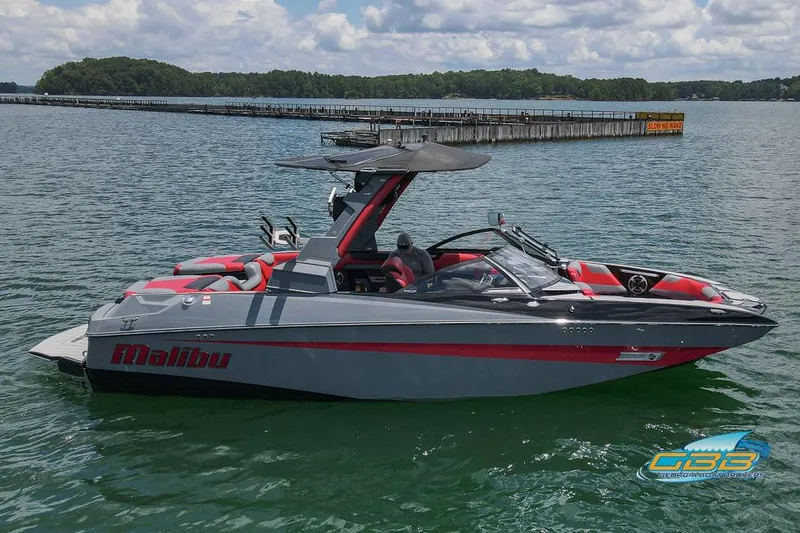 Slide: The Image of 2019 Malibu M235 boat on a lake with a dock in the background. - 4