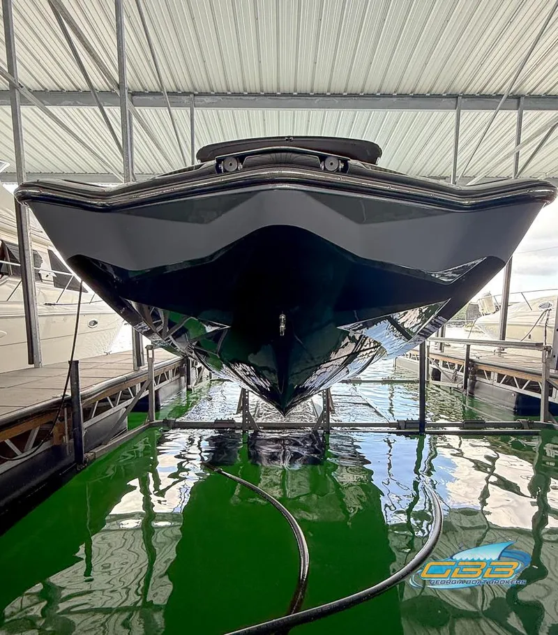Slide: The Image of 2019 Malibu M235 boat docked in a covered marina, reflecting on green water. - 40