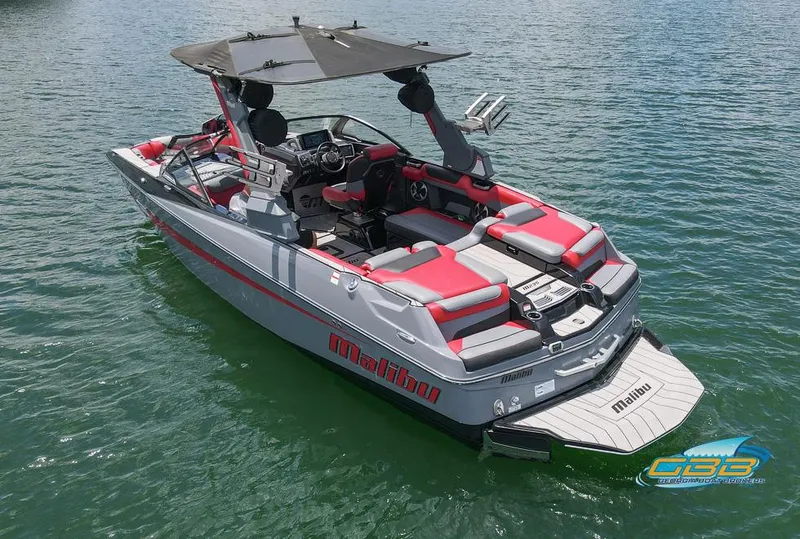 Slide: The Image of 2019 Malibu M235 boat with red and gray seating on a calm lake. - 6
