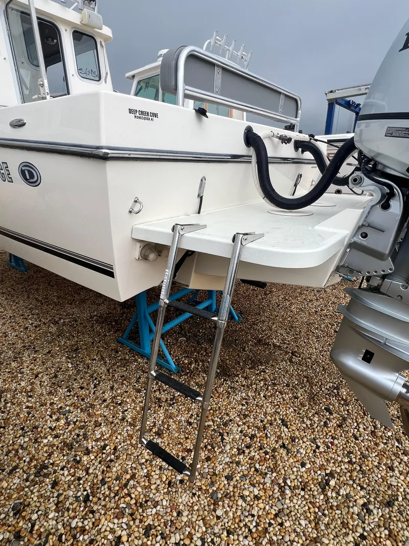Slide: The Image of 2021 Defiance Admiral 250 EX boat with ladder and outboard motor on gravel. - 18