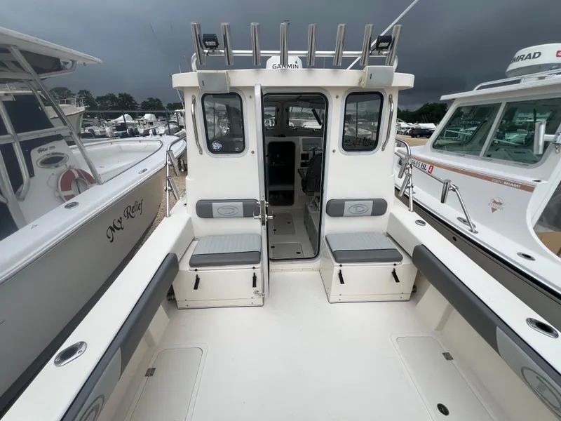 Slide: The Image of 2021 Defiance Admiral 250 EX boat interior with seating and storage, docked alongside other boats. - 33