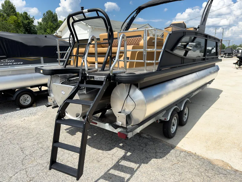 Slide: The Image of 2026 Godfrey AquaPatio 23' Flip Lounge Tritoon with ladder and trailer, parked outdoors. - 76
