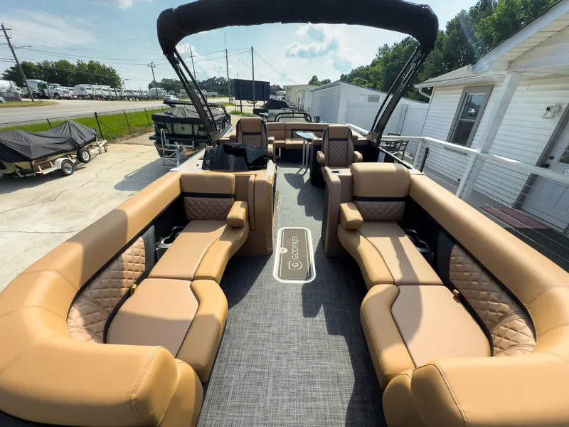 Slide: The Image of 2026 Godfrey Aquapatio 235 ULC Tritoon with luxurious tan seating and modern interior design. - 25