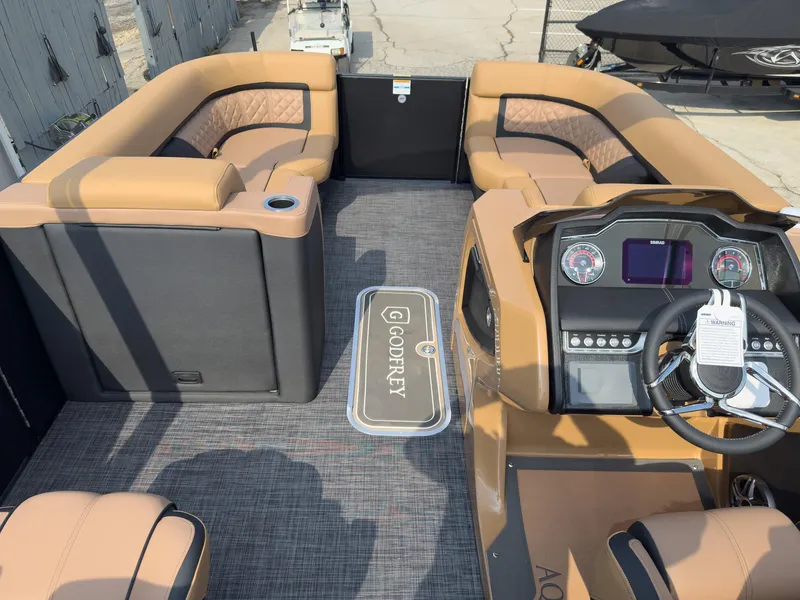 Slide: The Image of 2026 Godfrey Aquapatio 235 ULC Tritoon boat on trailer, sleek black design, outdoor setting. - 34