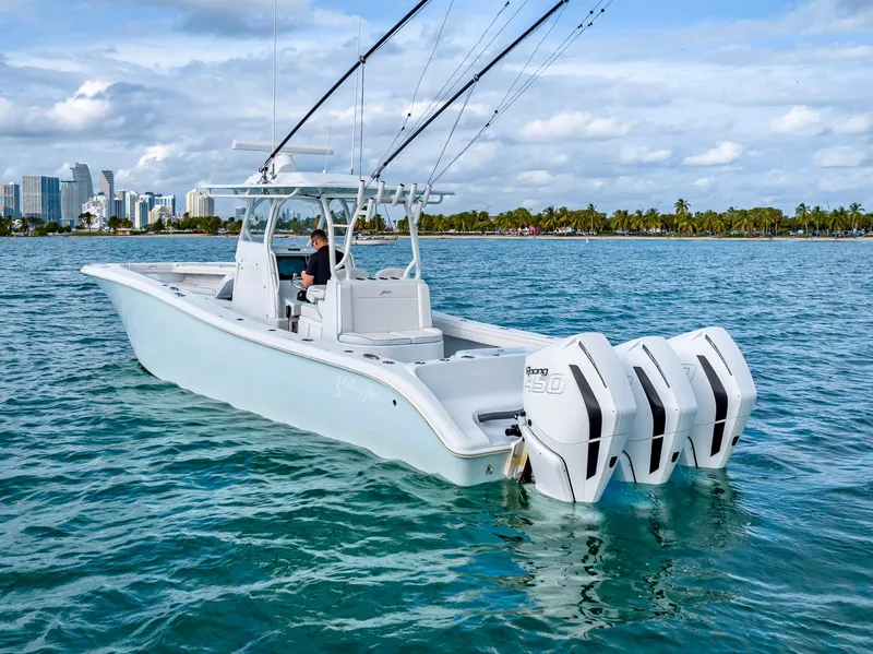 Slide: The Image of 2023 Yellowfin 36 boat with triple engines on blue water, city skyline in background. - 12