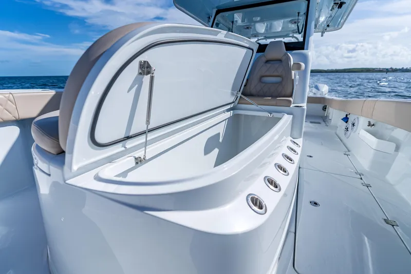 Slide: The Image of 2025 Freeman 35 boat interior with open storage compartment, luxurious seating, and ocean backdrop. - 43