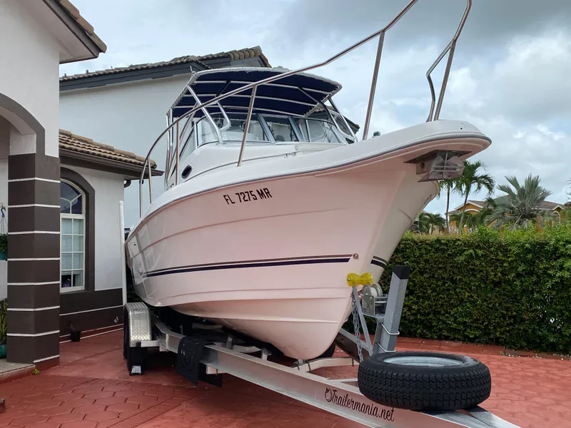 Slide: The Image of 2004 Cobia 250 Walk-Around boat on trailer, parked in residential driveway. - 10