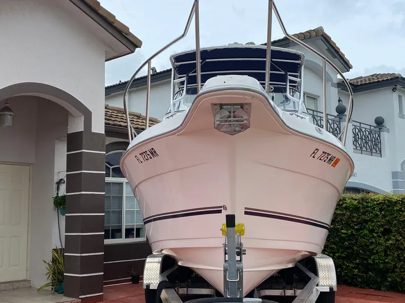 Slide: The Image of 2004 Cobia 250 Walk-Around boat on trailer in residential driveway. - 11